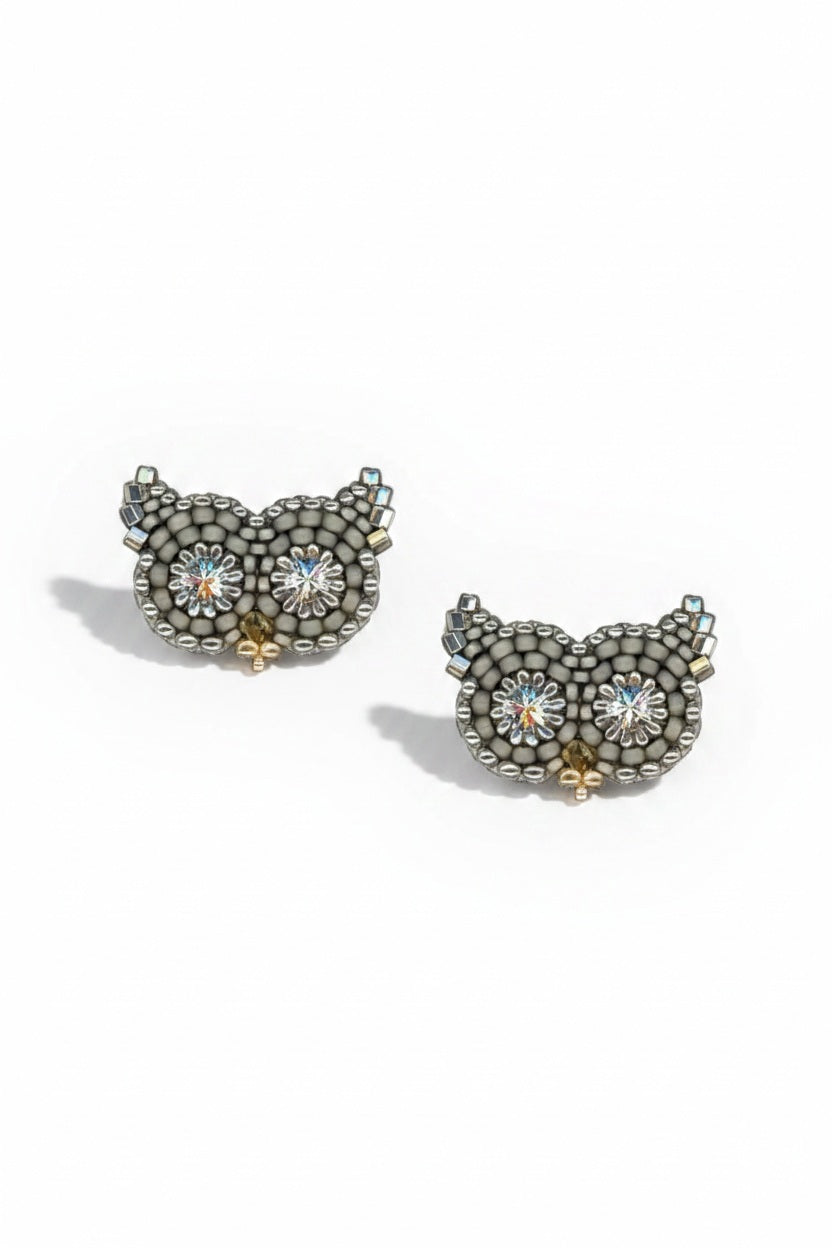 The MIGUEL ASES - OWL STUD EARRINGS WITH SWAROVSKI CRYSTAL by MIGUEL ASES, INC. are handcrafted in America and feature owl shapes with sparkling flower-like Swarovski crystal eyes, arranged on a white background.