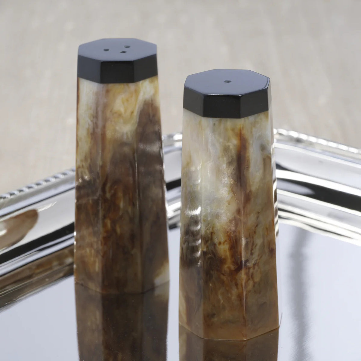 The ZODAX BURL WOOD DESIGN RESIN SALT AND PEPPER SHAKERS feature brown and beige marbled resin with black tops, beautifully displayed on a white background—ideal for resin decor enthusiasts.