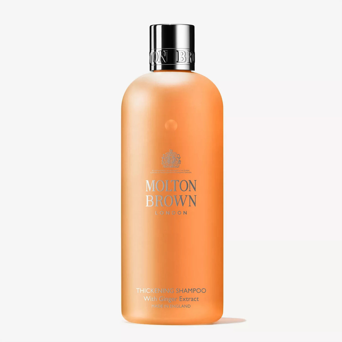 A translucent orange bottle of MOLTON BROWN - THICKENING SHAMPOO WITH GINGER for fine hair, featuring a shiny silver cap and crisp white text on the front.