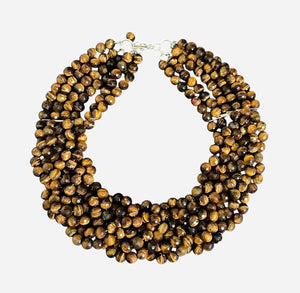 The ANN LIGHTFOOT Tiger Eye Braided Collier Necklace features multiple strands of polished brown beads in varied shades, twisted together with a glossy finish and finished with a sleek sterling silver clasp.
