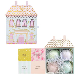 The MUSEE Dollhouse Bath Balm Set by MUSEE features a pastel-colored, house-shaped box with pink doors, six arched windows, gold roof detailing, and charming floral accents. “Anksee” is written in gold above the windows. Perfect as a children’s bath gift, this delightful packaging holds handcrafted natural bath products to make bath time extra special—all set against a light cream background.