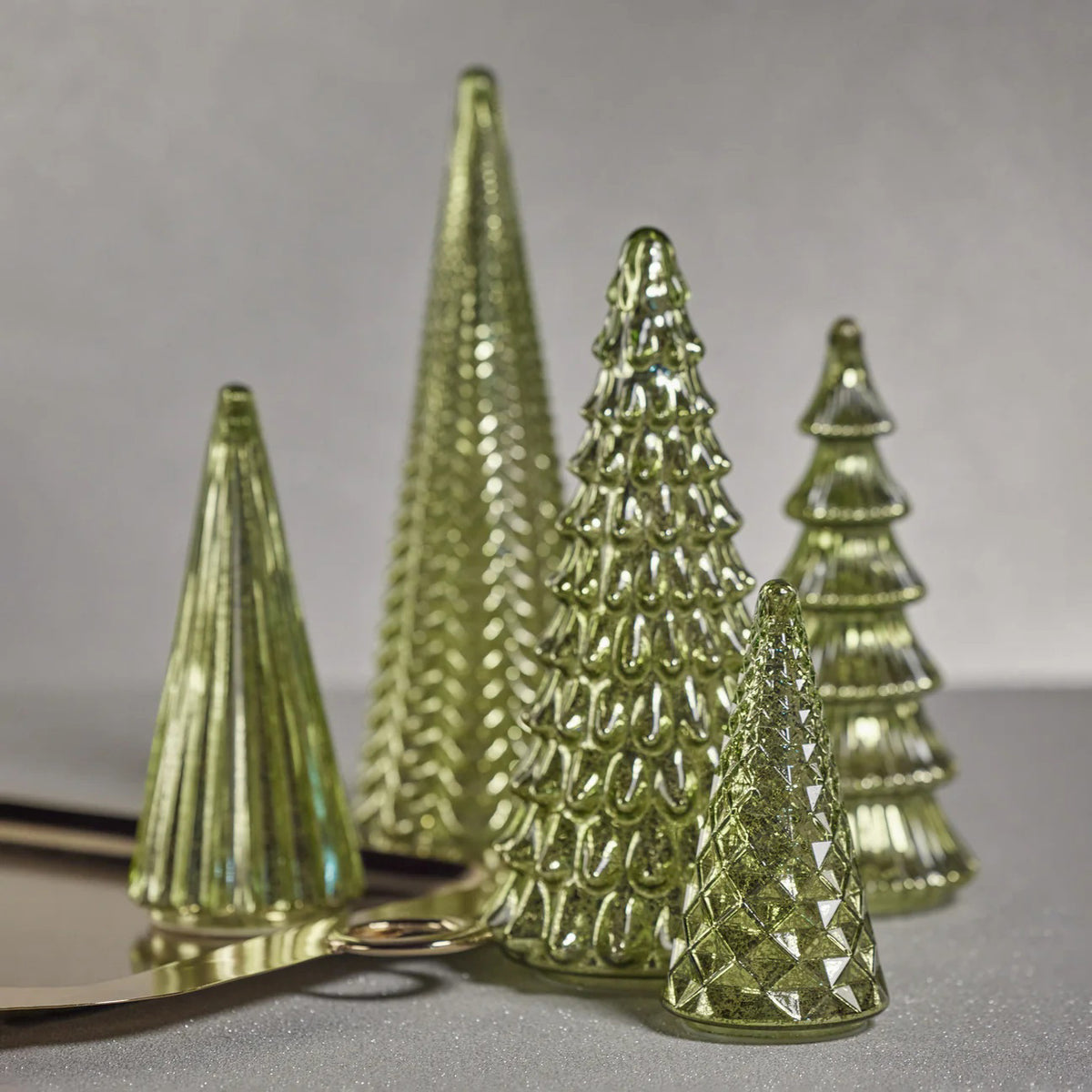 The ZODAX DAVOS LED ANTIQUE GLASS TREE 14.25 is a green glass ornament shaped like a stylized cone Christmas tree with a scalloped pattern, designed to stand upright on a white background.