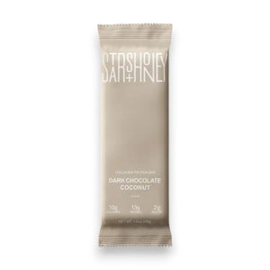 A STARS+HONEY - DARK CHOCOLATE COCONUT collagen protein bar is displayed on a coordinating beige background. The packaging emphasizes this low sugar protein bar from STARS+HONEY, highlighting that each bar contains 10g collagen, 13g protein, and only 2g sugar.