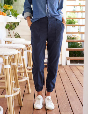 Introducing the FRANK & EILEEN JAMESON UTILITY JOGGER IN PERFORMANCE LINEN NAVY: a pair of high-rise jogger cargo pants crafted from textured Italian Performance Linen in a deep navy hue. These stylish joggers feature two front utility pockets, two large side pockets, an elastic waistband with belt loops, and elastic cuffs at the ankles. The pants are displayed on a plain white background.