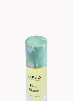 A 10ml bottle of LAFCO Fine Fragrance, First Bloom, a vegan eau de parfum that captures the freshness of spring with luminous neroli and radiant floral notes. Presented by LAFCO, this scent features a marbled green and white cap atop vibrant yellow liquid.