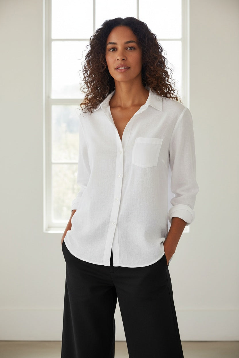 The EILEEN Relaxed Button-Up by Frank &amp; Eileen features a white chambray fabric with long sleeves, a chest pocket, and bust-flattering buttons. The collar displays "Frank &amp; Eileen EST. 1947," while the sleeves are slightly rolled for a casual look.