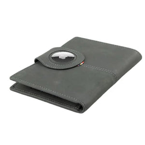 The GARZINI RFID-blocking leather passport holder in Carbon Black features multiple card slots, a pen holder, angled pockets, a transparent ID window, an Airtag compartment, and a snap-button closure flap.