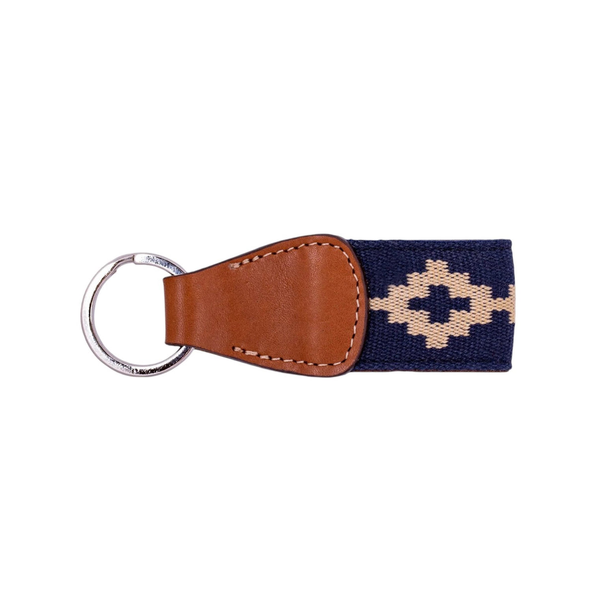 The LA MATERA - CORBINA WOVEN KEYCHAIN by LA MATERA features a silver metal ring, brown leather, and a navy blue strap with a beige diamond pattern inspired by Argentine artisan designs.
