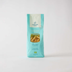 A light blue package of ATALANTA CORPORATION's CIPRIANI - ORGANIC DURUM WHEAT PENNE PASTA stands against a plain white background. The bag features a transparent window displaying the high protein index pasta inside and text detailing its Italian organic semolina content.