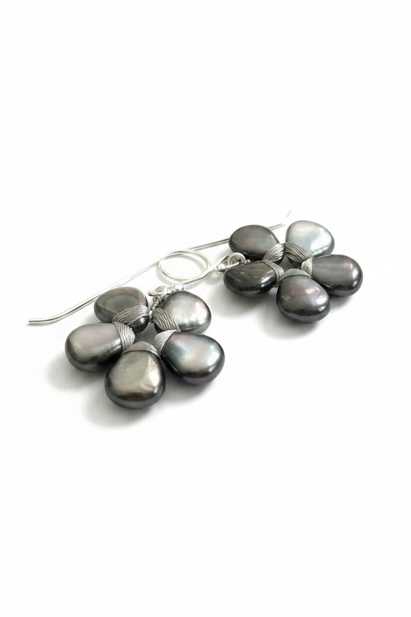 The ANN LIGHTFOOT – FLOWER EARRINGS OF BLACK LIP SHELL feature five dark iridescent teardrop stones in a floral pattern with silver wire accents, displayed against a plain white background.