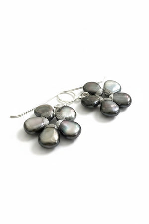 The ANN LIGHTFOOT – FLOWER EARRINGS OF BLACK LIP SHELL feature five dark iridescent teardrop stones in a floral pattern with silver wire accents, displayed against a plain white background.