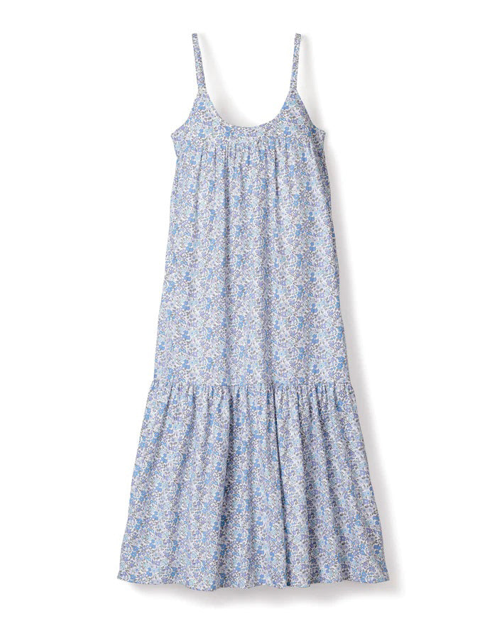 The PETITE PLUME - Fleur d&#39;Azur Chloe Nightgown is a sleeveless, knee-length sundress with thin straps, showcasing a beautiful blue and white floral pattern. Crafted from the finest quality cotton, this dress offers a loose, flowy fit and features a gathered section near the bottom hem, giving it a slightly ruffled look reminiscent of traditional nightwear from PETITE PLUME.