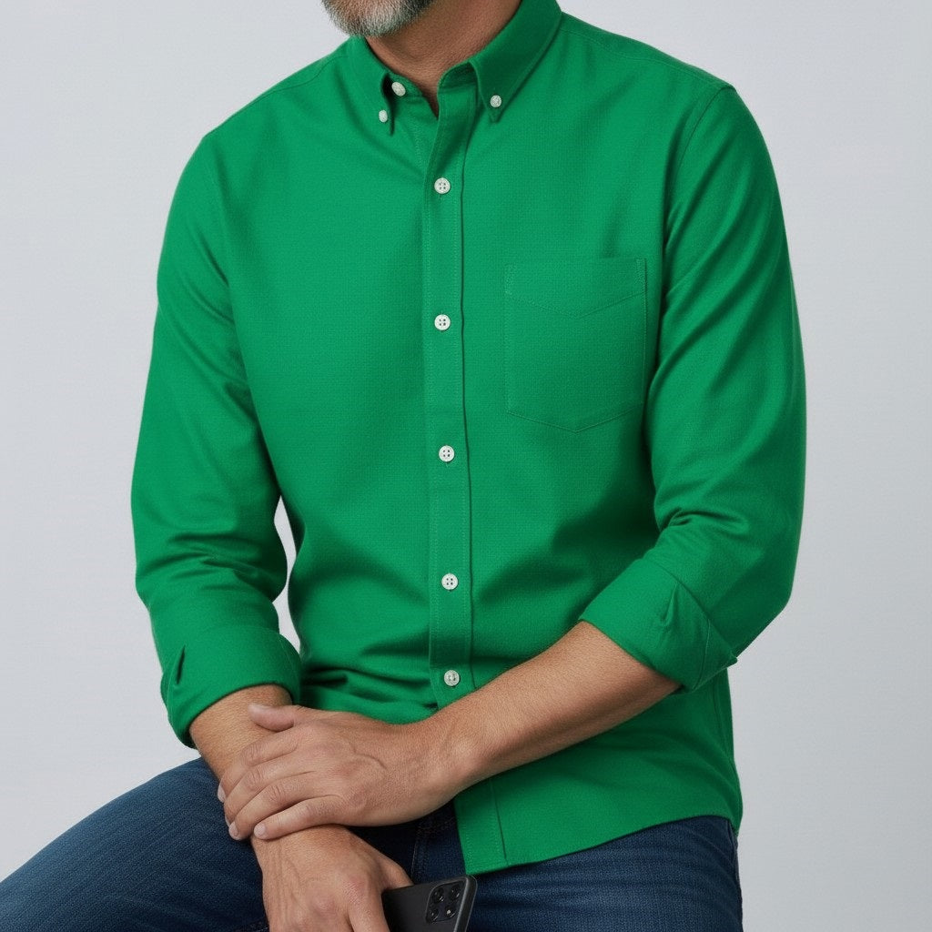 A man with short gray hair and a beard stands facing forward, wearing the FRANK &amp; EILEEN LUKE Men's Button Up Shirt in Famous Denim Birdie with rolled-up sleeves and dark blue jeans against a plain light gray background.