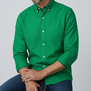 A man with short gray hair and a beard stands facing forward, wearing the FRANK & EILEEN LUKE Men's Button Up Shirt in Famous Denim Birdie with rolled-up sleeves and dark blue jeans against a plain light gray background.