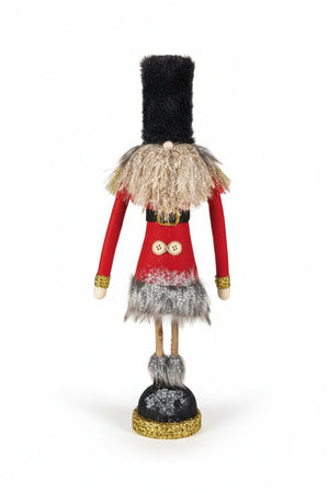 SOLDIER WITH GLITTER AND TWIG LEGS whimsical fabric figurine with a tall black hat, red coat, two buttons, and twig legs standing on a glittery gold and black base.