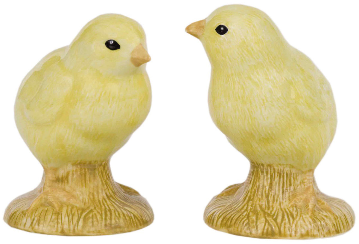 The QUAIL CERAMICS - CHICK SALT AND PEPPER SET by QUAIL DESIGNS features two hand-painted stoneware chick figurines with black eyes, each on a brown, nest-like base, positioned to face each other.