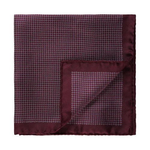 The AMANDA CHRISTENSEN Silk Pocket Square with Micro Pattern Twill in Bordeaux showcases a refined small-scale white geometric design on rich burgundy silk, elegantly folded to reveal the contrasting underside—a sophisticated addition to any men’s accessory collection.