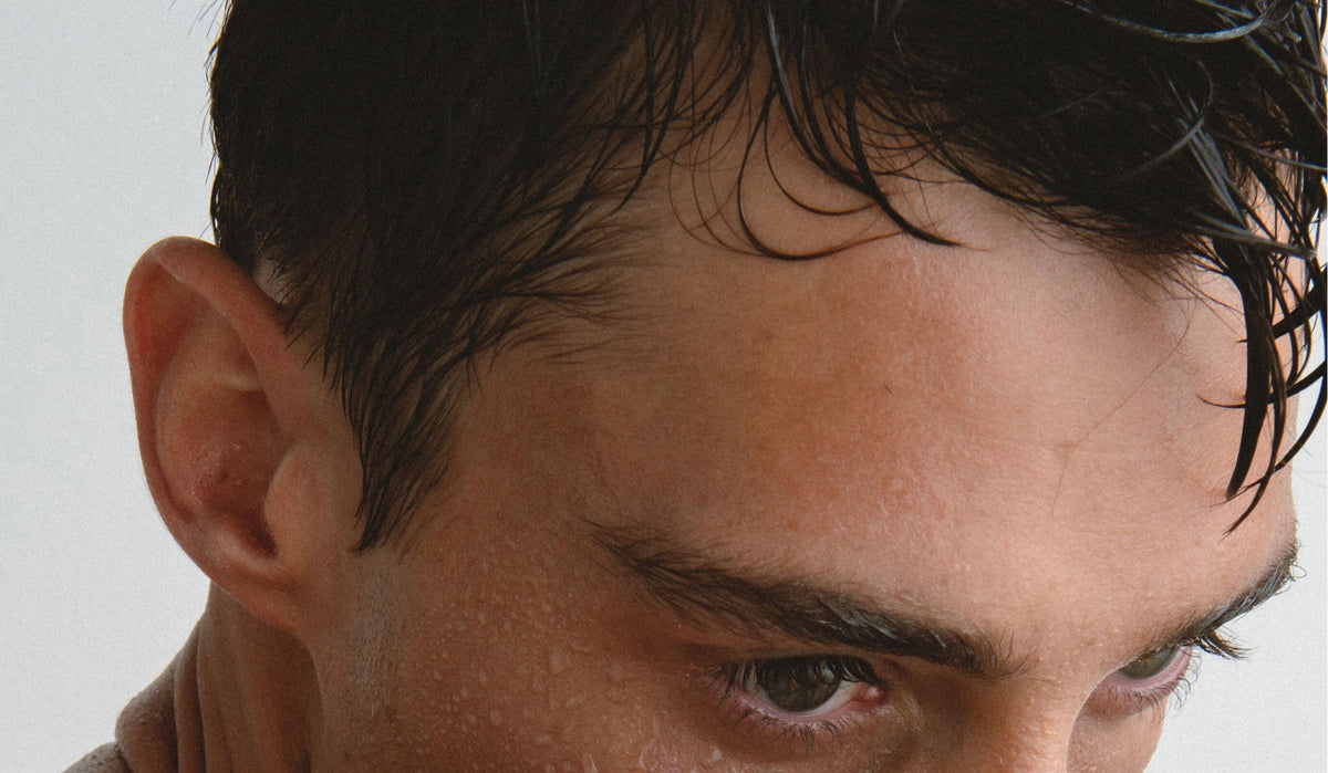 JACK HENRY - HAIR REFRESH is an organic sea salt spray with filtered spring water, witch hazel, pacific sea salt, and lemon oil—the perfect go-to for effortless beach hair. Shown: a sleek black bottle on a white background.