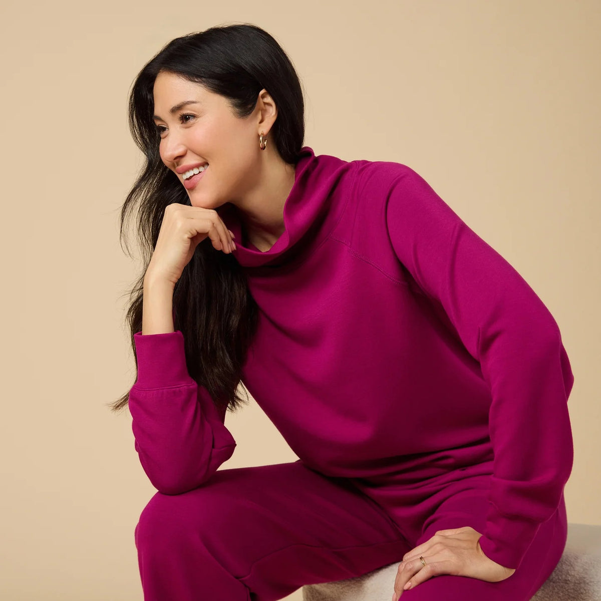 A woman seen from behind wearing the fuchsia SOFTIES - DREAMTECH COWL NECK WITH PLEATED PANT set featuring a long-sleeved cowl neck top and matching pleated pants.