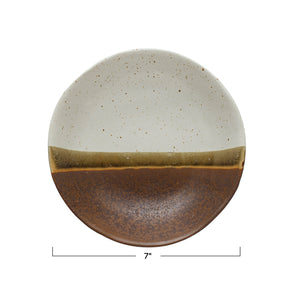 The STONEWARE LOW BOWL IN EARTH TONE REACTIVE GLAZE by CREATIVE COOP features a speckled off-white top, solid brown bottom, and an olive-brown stripe, highlighting handcrafted artistry with a beautiful reactive glaze finish.