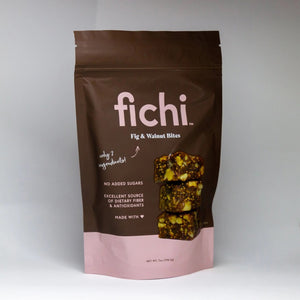A brown and pink resealable bag labeled FICHI FIG AND WALNUT BITES from FICHI shows snack bites. This vegan, gluten-free snack features no added sugars, dietary fiber, antioxidants, and simple ingredients.