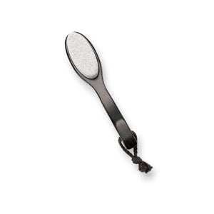 A two-sided foot file with a wooden handle and attached rope, featuring natural pumice on one side and a black abrasive surface on the other. The product, BAUDELAIRE - BEECHWOOD 8" FOOT FILE by BAUDELAIRE, is laid next to its box, which has a botanical design and the branding "Beechwood Foot File" inspired by Japanese rituals.