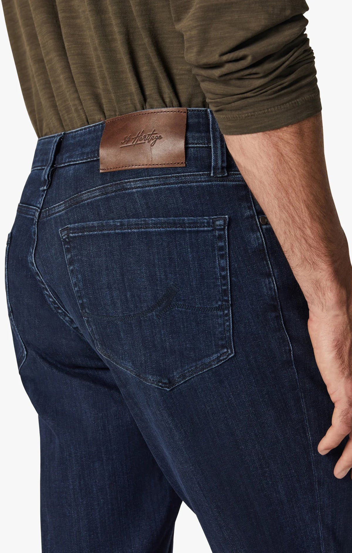 A man in a green long-sleeve shirt, brown shoes, and 34 HERITAGE Charisma Relaxed Straight Leg Jean in Dark Midnight Brushed Urban wash stands with his back to the camera against a plain white background.