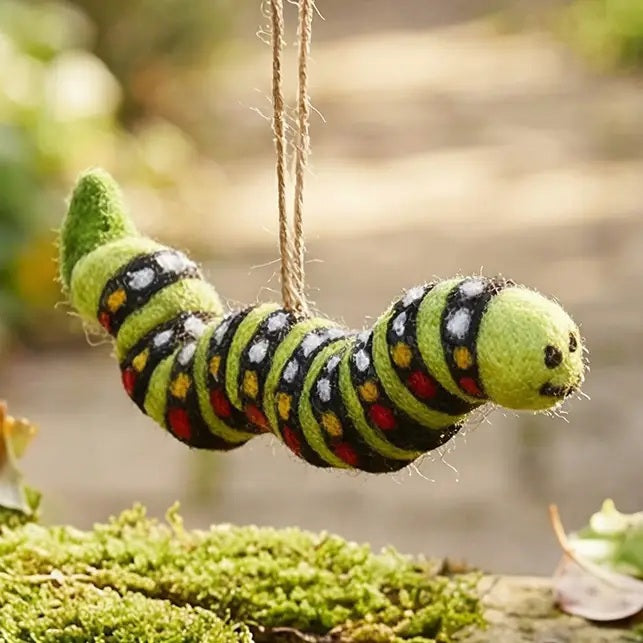 CARL THE CATERPILLAR ORNAMENT by FELT SO GOOD: a felt organic caterpillar toy with a green, black, yellow, and red patterned body, hanging from a green string made of sustainable materials.