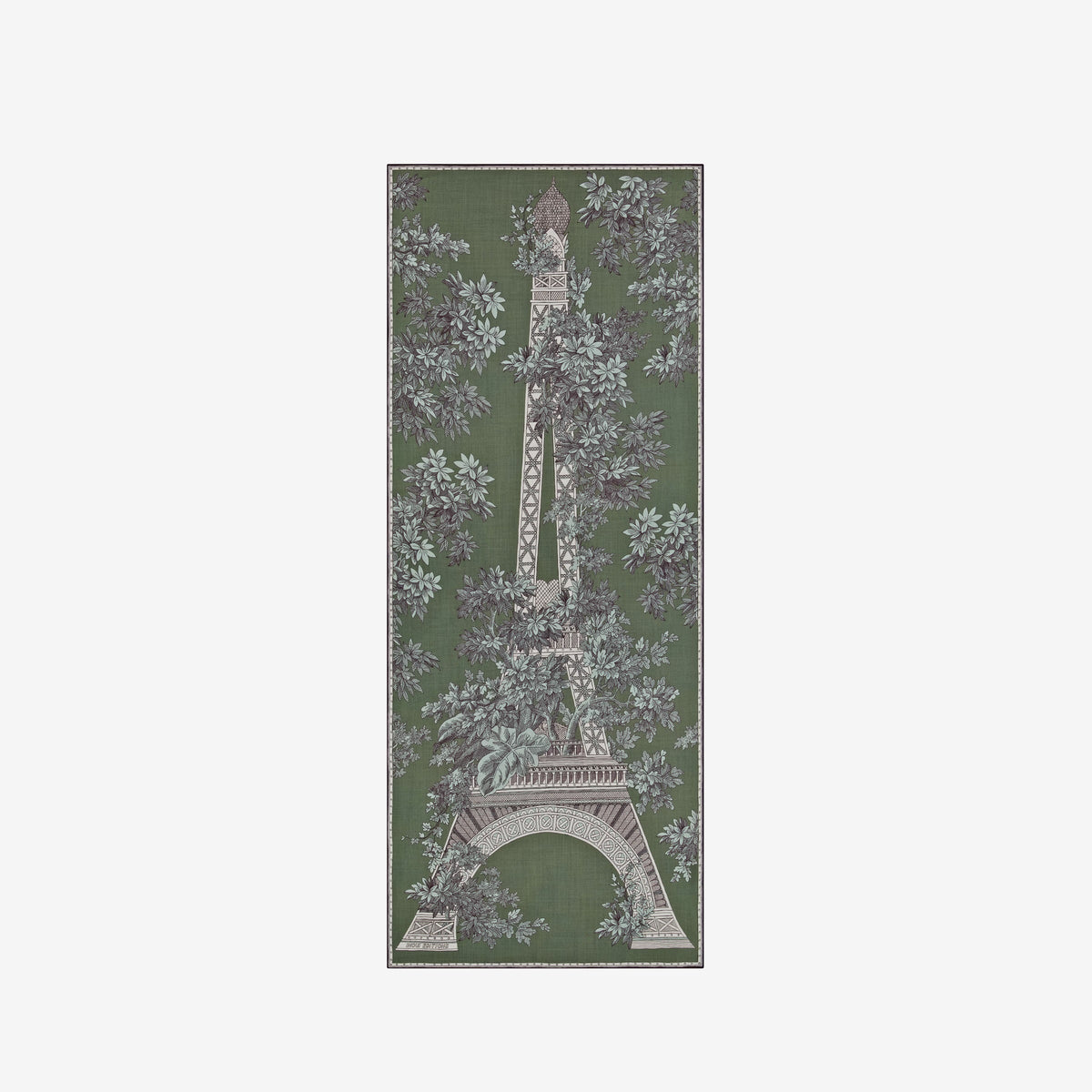 A person with short hair wears a long black dress and the INOUI EDITIONS 1889 WOOL SCAR FIN KHAKI scarf by INOUI—a green patterned accessory featuring intricate floral and geometric designs, crafted from 100% wool in India—while standing against a plain white background.