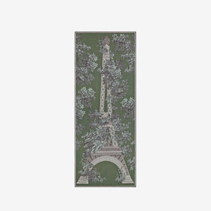 A person with short hair wears a long black dress and the INOUI EDITIONS 1889 WOOL SCAR FIN KHAKI scarf by INOUI—a green patterned accessory featuring intricate floral and geometric designs, crafted from 100% wool in India—while standing against a plain white background.