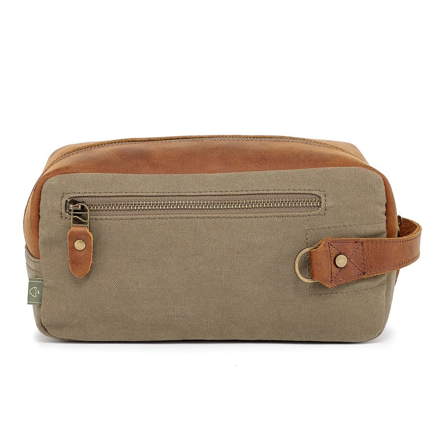 The TSD BRAND Valley Oak Toiletry Bag in olive is a rectangular, handcrafted travel essential made from durable canvas, featuring a tan leather strap and a small leather patch for added style.