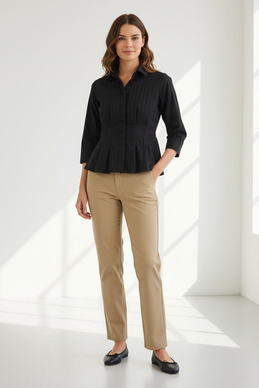 A person wearing the HINSON WU - MARTINA 3/4 SLEEVE SHIRT IN CLASSIC STRIPE BLACK, a button-down blouse with subtle vertical stripes by HINSON WU, paired with beige pants, stands against a plain light background.