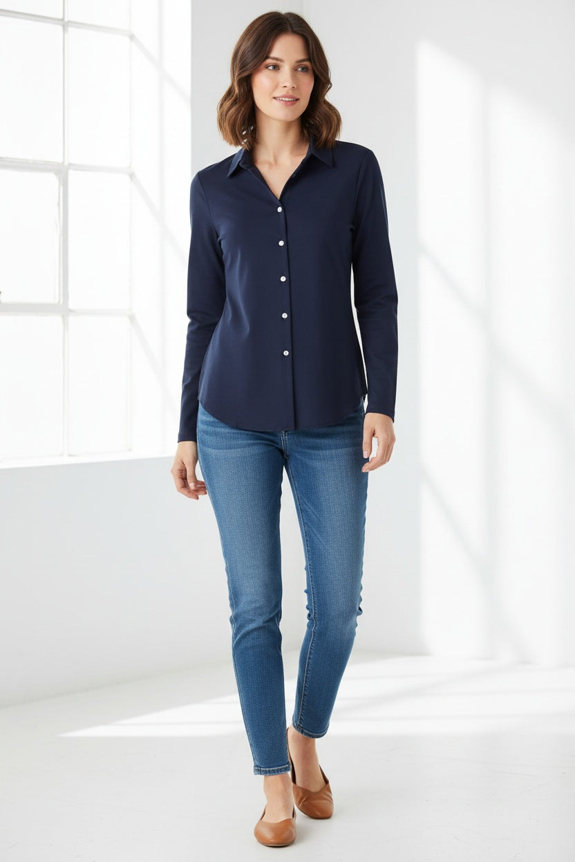 A woman stands against a white wall, wearing the HINSON WU - DONNA Long Sleeve Wing Collar “T” Shirt in navy and black pants. Her hands are relaxed at her sides, and her face is partially out of frame.
