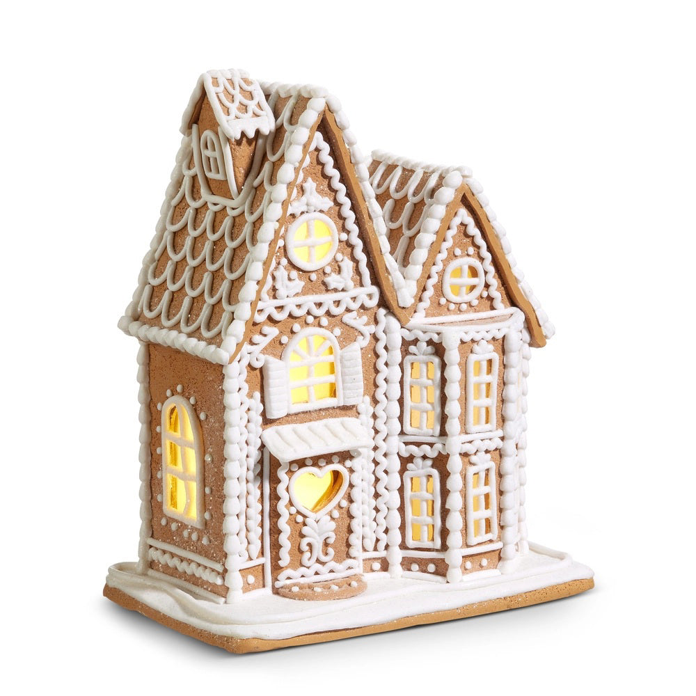The RAZ IMPORTS LIGHTED GINGERBREAD HOUSE 12&quot; features two peaked roofs, white icing details, and glowing yellow battery-operated lights with a 6-hour timer for a warm, festive holiday display.