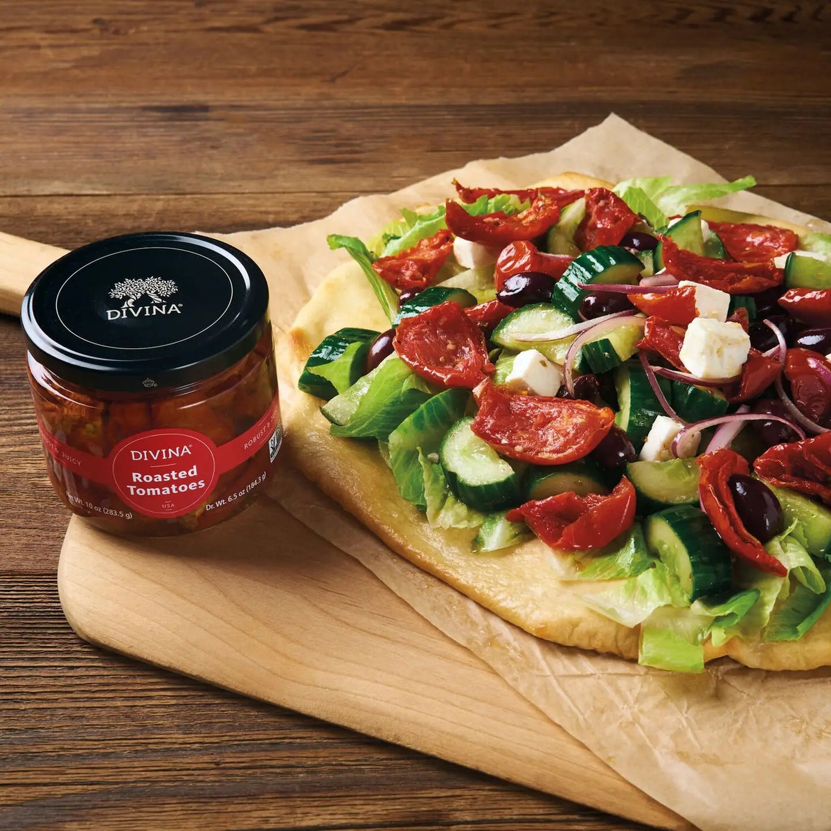 A glass jar of DIVINA Roasted Tomatoes with a black lid displays the marinated, USA-grown tomatoes inside. The label is red with white text, and the net weight is 10 oz (283.5 g).