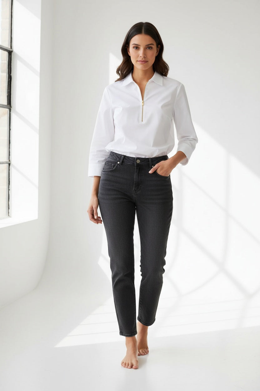 A woman stands against a plain, light background wearing the HINSON WU Alessa 3/4 Sleeve Shirt in stretch polished cotton—a crisp white blouse with a collared neckline and partial front zipper—paired with dark pants.