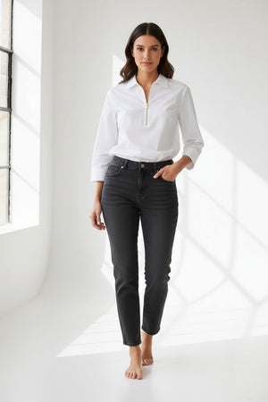 A woman stands against a plain, light background wearing the HINSON WU Alessa 3/4 Sleeve Shirt in stretch polished cotton—a crisp white blouse with a collared neckline and partial front zipper—paired with dark pants.