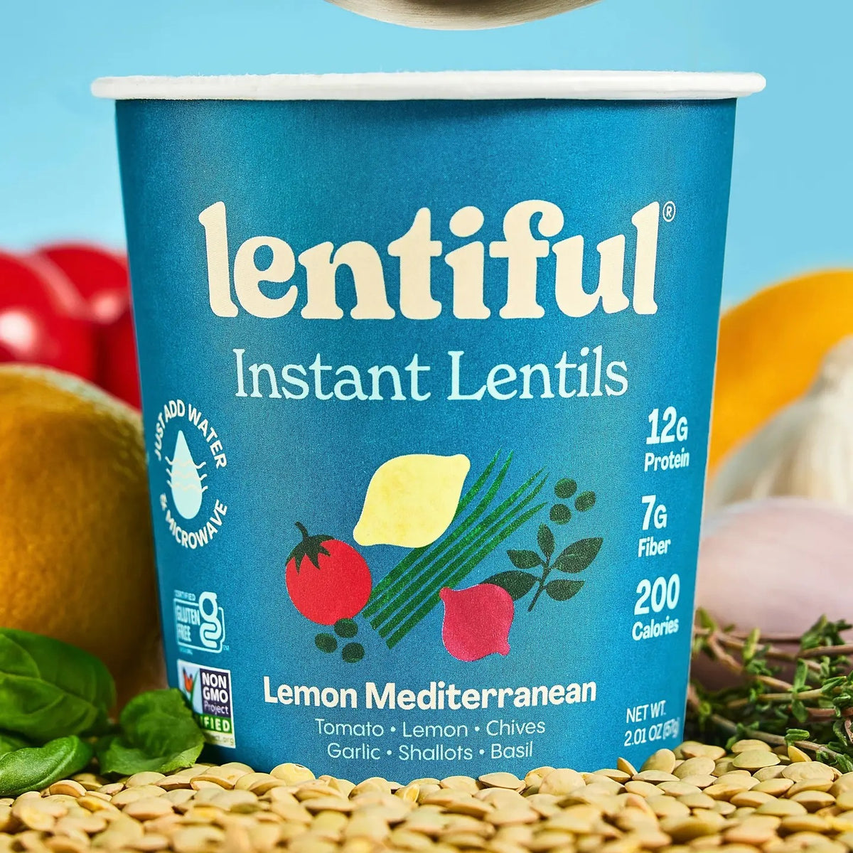 A blue container of LENTIFUL - LEMON MEDITERRANEAN INSTANT LENTILS by LENTIFUL, highlighting vibrant imagery of lemon, tomato, and herbs. Inspired by classic Greek cuisine, this plant-powered option offers 12g protein, 7g fiber, and 200 calories per serving. The label features the Non-GMO Project Verified seal, making it a nutritious pick for those seeking a Blue Zone-inspired lifestyle.