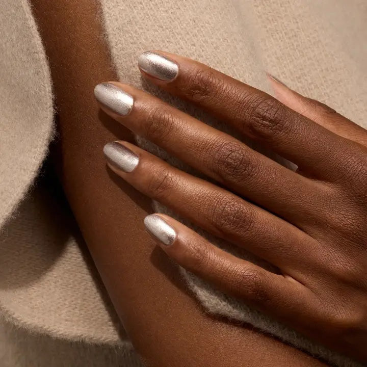 A transparent glass bottle of MANUCURIST - GREEN™ Nail Polish in Disco by MANUCURIST INC contains a sparkling silver glitter vegan polish. The bottle features a black cap and a white label adorned with green and black text.