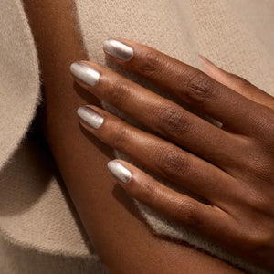 A transparent glass bottle of MANUCURIST - GREEN™ Nail Polish in Disco by MANUCURIST INC contains a sparkling silver glitter vegan polish. The bottle features a black cap and a white label adorned with green and black text.