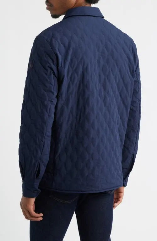 A man wears the SAVE THE DUCK Anton Jacket in navy—a dark blue, water-resistant jacket with buttoned chest pockets and a collar—paired with dark pants, standing against a plain white background.