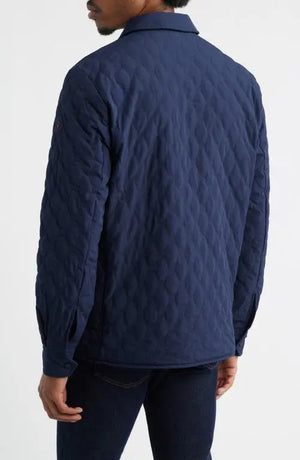 A man wears the SAVE THE DUCK Anton Jacket in navy—a dark blue, water-resistant jacket with buttoned chest pockets and a collar—paired with dark pants, standing against a plain white background.