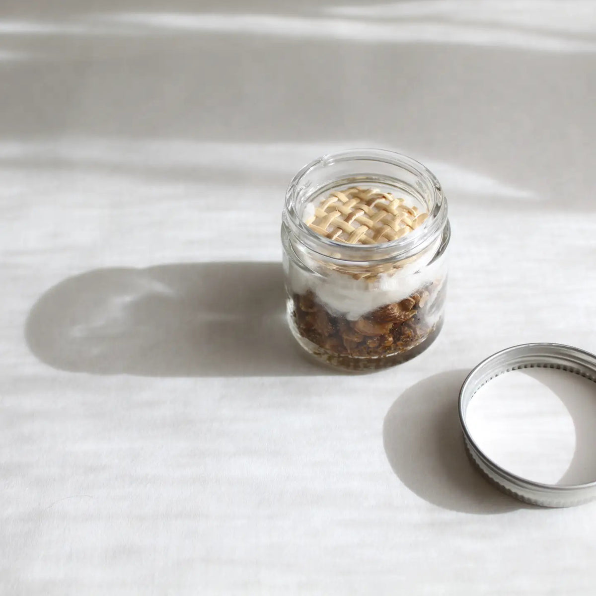 A small glass jar with a white lid labeled "MADISON AND GREEN - AT YOUR DESK FOCUS BOOST AROMATHERAPY INHALER" by MADISON GREEN contains a blend of dried herbs for stress relief, shown against a plain white background.