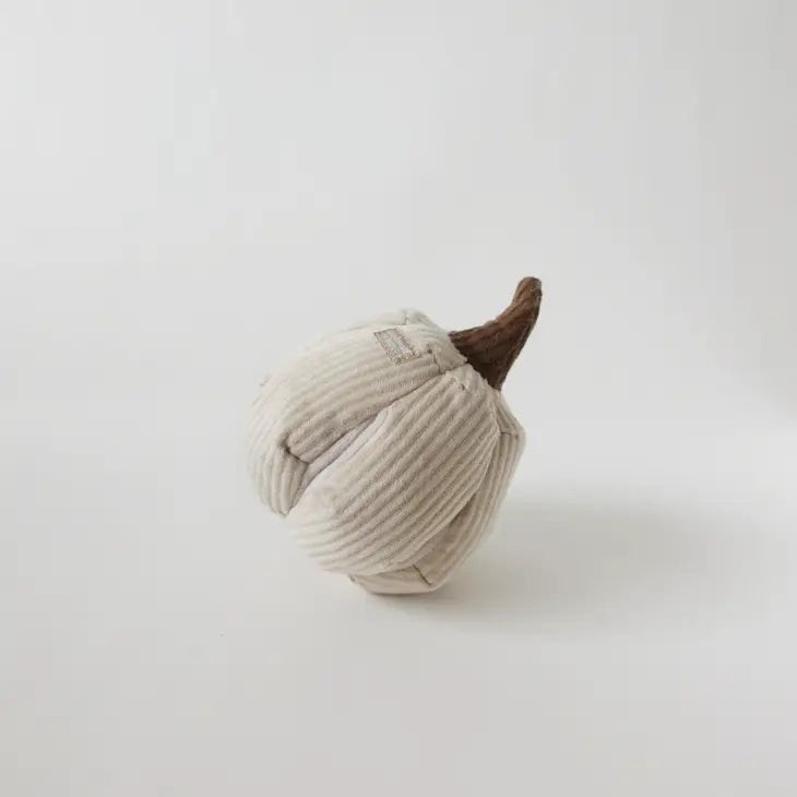 A small, plush pumpkin made of beige corduroy fabric with a brown stem rests on a white surface. The neutral background enhances the simple, handcrafted design of this LAMBWOLF COLLECTIVE - BOO DOG TOY from LAMBWOLF COLLECTIVE, which features treat pockets for added fun.