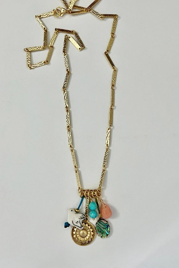 A woman with long brown hair, smiling at the camera in a sleeveless white top, wears the SANDRINE FRANCE STUDIO - SOLANA NECKLACE by SANDRINE FRANCE STUDIO, standing against a plain light background.