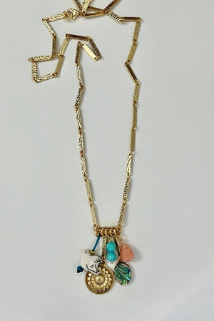 A woman with long brown hair, smiling at the camera in a sleeveless white top, wears the SANDRINE FRANCE STUDIO - SOLANA NECKLACE by SANDRINE FRANCE STUDIO, standing against a plain light background.