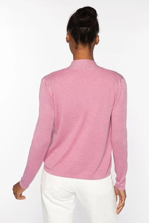 A woman stands against a white background, wearing the KINROSS CASHMERE Open Rib Linen Cardigan by KINROSS over a matching top and white pants, hands in her pockets with a relaxed expression.