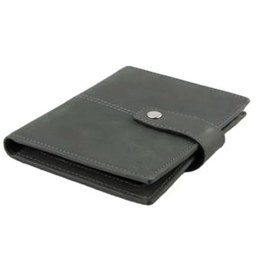 The GARZINI RFID-blocking leather passport holder in Carbon Black features multiple card slots, a pen holder, angled pockets, a transparent ID window, an Airtag compartment, and a snap-button closure flap.