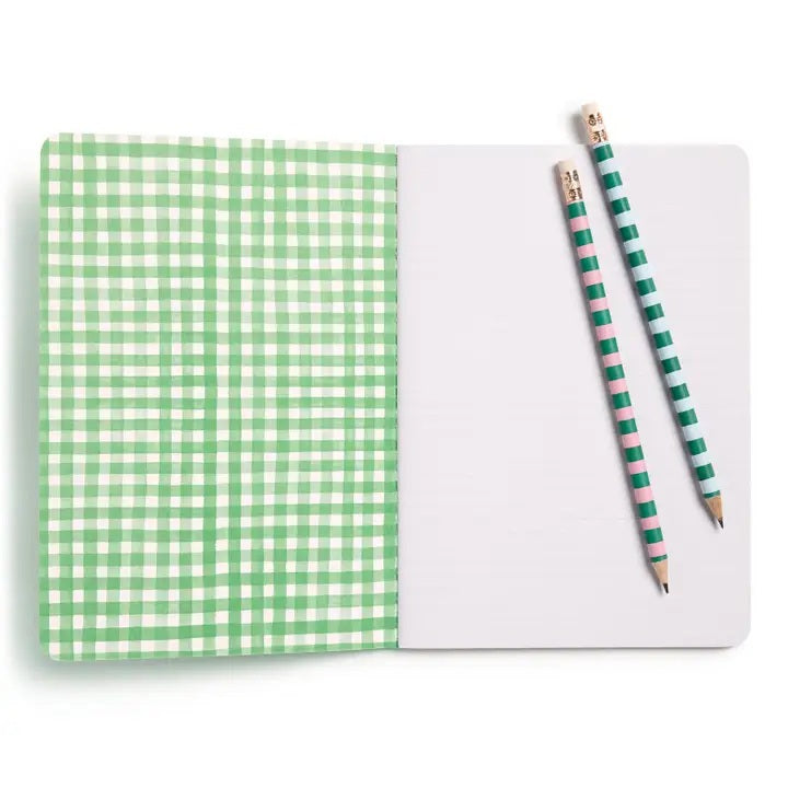 The E. FRANCES PAPER STITCHED NOTEBOOKS GARDENER, SET OF 2, featuring a green and white checkered cover, is open on a white surface next to two striped pencils—one green and one pink—with the right page blank.