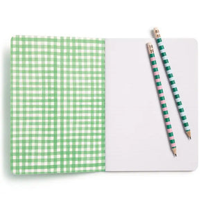 The E. FRANCES PAPER STITCHED NOTEBOOKS GARDENER, SET OF 2, featuring a green and white checkered cover, is open on a white surface next to two striped pencils—one green and one pink—with the right page blank.